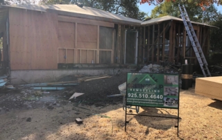 Building a new house. Image of a Green Group remodeling sign in front of a house that is studs and plywood during a build.