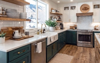 Bright kitchen interior with green-painted maple cabinets, abundant indoor plants, and sunlight streaming through the windows, creating a fresh and inviting atmosphere.